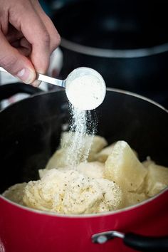 someone is sprinkling sugar on some food in a red pot with a ladle