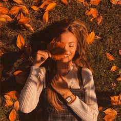 a woman laying on the ground with leaves around her