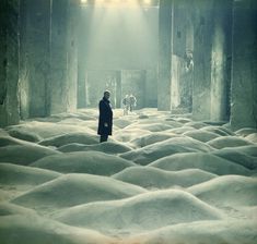 a man standing in the middle of a room filled with white snow and light shining down on him