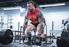 a man squats down while holding a barbell in a crossfit gym