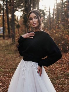 a woman in a black sweater and white tulle skirt posing for the camera with her hands on her hips