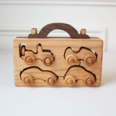 a wooden toy train case with wheels on the front and sides, sitting on a white surface