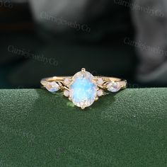 an opal and diamond ring sitting on top of a green surface