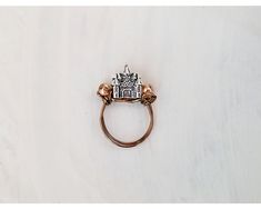 a ring with a house on it sitting on top of a white table next to a pair of scissors