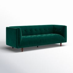 a green velvet couch with wooden legs and buttons on the back, viewed from the front