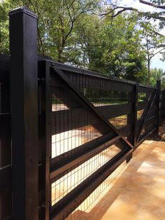 a black gate that is next to some trees