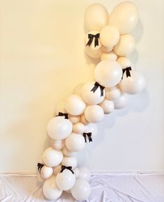 white balloons with black bows are arranged in the shape of a number one on a wall