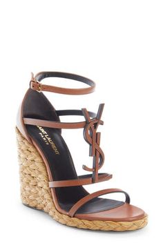 A tonal YSL logo dominates the front of this strappy calfskin sandal given a vacay-ready update with a braided-raffia wedge. 4" (105mm) heel; 1/2" platform (size 37) Adjustable ankle strap with buckle closure Leather/synthetic upper, leather lining and leather/synthetic sole Made in Italy Women's Designer Shoes Designer Wedges, Ysl Heels, Ysl Logo, Girly Shoes, Casual Heels, Fabulous Shoes, Footwear Design Women, Handbag Shoes, Shoe Obsession