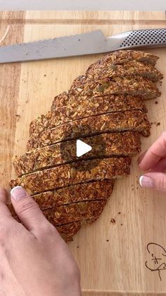 a person cutting up food on top of a wooden cutting board next to a knife