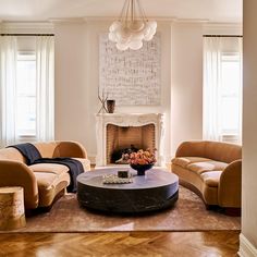 a living room with two couches and a table in front of a fire place