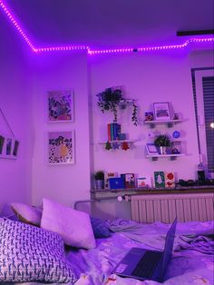 a laptop computer sitting on top of a bed in a room filled with purple lights