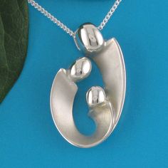 "Mother of two children pendant may also be interpreted as celebrating your family of three! Our expressive, egg-shaped creation is hand sculpted in sterling silver. Size: 1\" X 3/4\": $145. Bright polished heads and raised curves are contrasted with recessed contours that have a soft satin finish. Fully finished reverse. This dimensional pendant includes a sterling chain that threads through the design's integrated and invisible chain bail. The included US-made 1.2mm curb link chain with spring Unique Sterling Silver Jewelry For Keepsake, Silver Oval Necklace For Anniversary, Silver Oval Necklace For Anniversary Gift, Sterling Silver Oval Pendant Necklace For Mother's Day, Sterling Silver Oval Pendant Necklace As Gift For Mom, Hand Cast Oval Pendant Jewelry Gift, Silver Oval Pendant Jewelry For Mom, Sterling Silver Oval Necklace For Mom, Hand Cast Pendant Jewelry For Anniversary