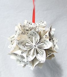 an ornament made out of sheet music is hanging from a red string on a white surface