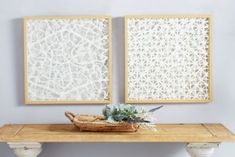 two framed pictures on the wall above a table with a basket and succulents