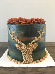 a green cake with gold decorations and a deer on it's head is sitting on a white plate