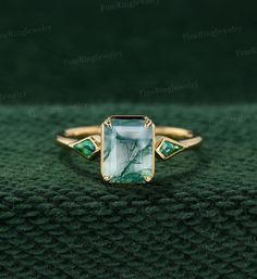 a green and white stone ring sitting on top of a green cloth