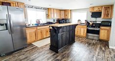 a kitchen with wooden cabinets and stainless steel appliances in the center, along with hardwood flooring