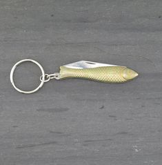 a fish shaped keychain is shown on the ground with a hook in it's mouth