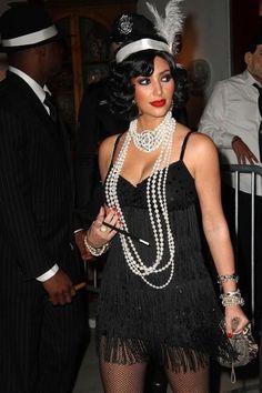 a woman in a black dress and hat with pearls