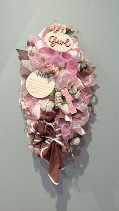 a pink and brown wreath hanging on the side of a wall with a name tag