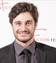 a man in a suit and tie smiling at the camera