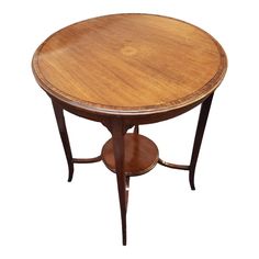 a round wooden table with two small shelves on the bottom and one shelf below it