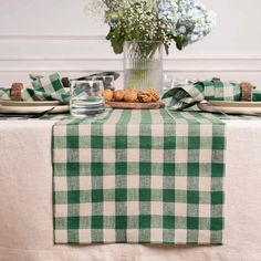 a green and white checkered table cloth on a dining room table with flowers in a vase