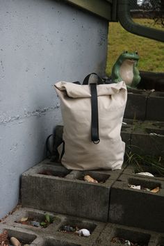 a white bag sitting on the steps next to a cement wall and green frog statue