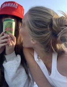 two women are kissing each other while holding cans