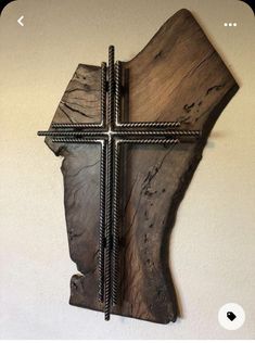 a wooden cross hanging on the wall next to a white wall with a metal frame