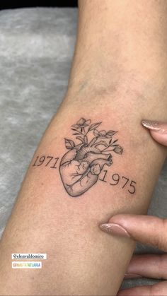 a woman's arm with a heart and flowers tattoo on the left side of her arm