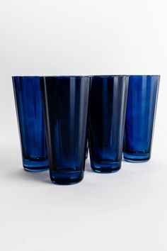 three blue glasses sitting next to each other on a white surface with no one in it