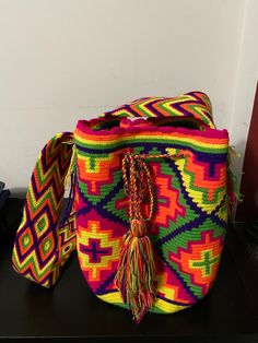 a multicolored bag sitting on top of a black table next to a white wall