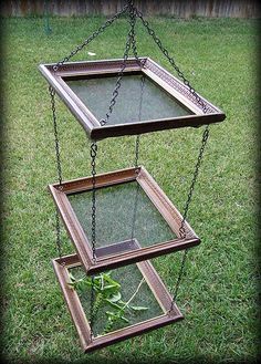 three tiered glass planter with metal chains hanging from it's sides in the grass