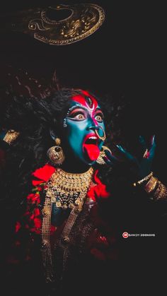 a woman with painted face and body is holding her hand up to her mouth as she poses