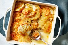 a casserole dish with meat and vegetables in it on a blue towel next to a spoon