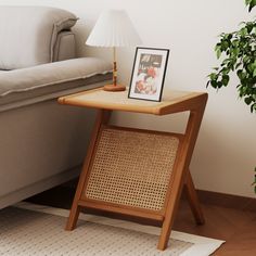 a small wooden table sitting next to a couch with a lamp on top of it