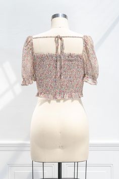 A sweet and simple versatile wardrobe staple perfect for summer, the Emily cropped blouse features a smocked elastic bodice, short sleeves with smocked cuffs, a cropped hem, and a pretty floral-print chiffon. Please Note- This item is final sale only. . Details: S: Bust 34", Length 18" M: Bust 36", Length 18.5" L: Bust 38", Length 19" Length Measured from Shoulder Unlined Material: 100% Polyester Facing: 100% Rayon Imported Gentle Wash Cold / Line Dry Floral Print Smocked Top With Square Neck For Summer, Summer Floral Print Smocked Top With Square Neck, Feminine Floral Print Smocked Top For Summer, Feminine Floral Smocked Top For Summer, Summer Feminine Floral Print Smocked Top, Spring Vacation Smocked Top With Square Neck, Feminine Summer Smocked Top With Floral Print, Fitted Smocked Top With Short Sleeves, Square Neck Crop Top For Spring Vacation