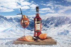 a bottle of alcohol sitting on top of a wooden cutting board next to an orange slice