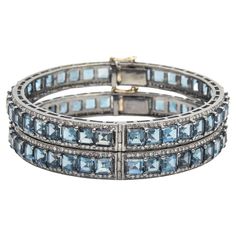 Pair of London blue topaz and diamond bangles mounted in sterling silver with a 14k gold tongue clasp and safety. Each bracelet contains princess cut blue topaz prong set down the center with round diamonds along the side edges.  The 2 bracelets have a combined carat weight of 5.28 carats in diamonds and 61.23 in London blue topaz.  Internal circumference is 7.12".  across inside 2 3/8" by 2 5/16" Luxury Blue Topaz Jewelry With Rose Cut Diamonds, Luxury Jewelry With Rose Cut Diamonds And Blue Topaz, Fine Jewelry Blue Topaz Bracelets, Luxury Blue Topaz Gemstone Bracelets, Luxury Blue Topaz Bracelets, Formal Stackable Blue Topaz Jewelry, Elegant Blue Topaz Jewelry With Single Cut Diamonds, Blue Topaz Bangle Jewelry, Blue Topaz Gemstone Bangle Jewelry