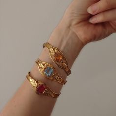 Description: This listing is for ALL THREE of the bracelets. You will receive all three of the bracelets shown in this listing. They all date to the Art Deco era so are most likely from the 1920s or 1930s. All of the are made of metal with a gold tone and feature a central rhinestone. One is red, one is yellow and the other is blue. The all open with a hinge button. There are no maker's marks. Condition: All three are in very good vintage condition. They all work perfectly fine and the stones ar Adjustable Heirloom Jubilee Bracelet, Vintage Gold Hand Cast Cuff Bracelet, Gold Art Deco Jewelry For Ceremonial Occasions, Heirloom Gold Gemstone Bracelets, Yellow Gold Art Deco Bracelet, Heirloom Gemstone Bracelet Jewelry, Heirloom Gemstone Bracelet, Art Deco Gemstone Bracelet For Formal Occasions, Heirloom Style Gold Bracelets With Jewels