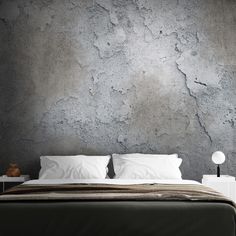 a bedroom with concrete walls and white pillows on the bed, along with two nightstands