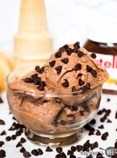 two scoops of chocolate ice cream in a glass bowl with cookies on the side