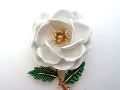 Vintage Floral Jewelry - This is a gold tone brooch with white enamel flower and green enamel leaves. It is signed Trifari with a crown over the T and measures almost 2.25" by 1.25". Elegant White Enamel Pin, Formal White Enamel Pin Brooch, Formal White Enamel Pin, Flower-shaped Enamel Brooches For Wedding, Flower Shaped Enamel Brooches For Wedding, Wedding Flower-shaped Enamel Brooches, White Flower Enamel Pin For Wedding, Vintage White Flower Enamel Pin, White Flower-shaped Enamel Brooches