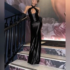 a woman in a black dress standing on some stairs