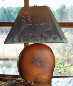 a lamp sitting on top of a wooden table next to a window with a bear etched in it