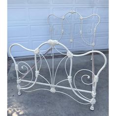 a white iron bed frame with intricate designs