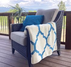 a blue and white blanket sitting on top of a chair next to a potted plant