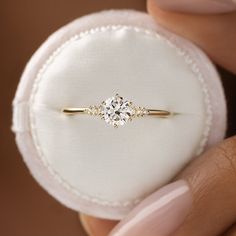 a close up of a person's hand holding a ring with a diamond on it