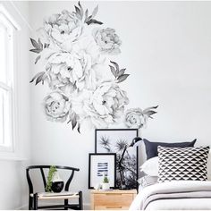 a bed room with a neatly made bed and white flowers on the wall above it